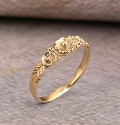 a gold ring with flowers and leaves on the side, sitting on top of a cloth