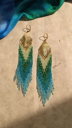 ♀ Bohemian seed beaded earrings handmade with glass satin beads, brass, agate stones, and nylon thread.. ♀ Drop Height: 6 in. ♀ Beads: Toho, Miyuki, Czech ♀ Ear Wire: 18k gold-plated brass ♀ Thread: Nylon ♀ Nickel Free Get 20% off when you shop from my website! link to earrings below! https://moonandmilk.com/products/hallie-aqua-green-seed-bead-earrings use code: ETSY20 Affordable Green Beaded Earrings For Beach, Multicolor Beaded Brass Earrings, Festival Brass Jewelry With Tiny Beads, Bohemian Long Drop Jewelry With Tiny Beads, Beaded Dangle Earrings In Brass, Beaded Brass Earrings For Festival, Bohemian Gold Earrings With Faceted Beads, Gold Beaded Chain Earrings For Festival, Gold Beaded Earrings With Beaded Chain For Festival