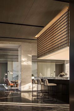 an open kitchen and dining area with marble flooring, counter tops and barstools