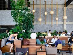 people sitting at tables in a restaurant with plants and potted plants on the walls