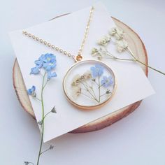 a necklace with blue flowers on it sitting on top of a piece of paper