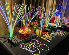 a table topped with lots of neon colored sticks and bowls filled with candy canes