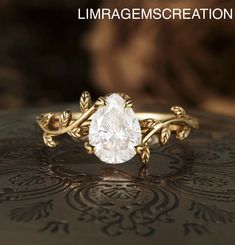 a close up of a gold ring with a white diamond in the center and leaves on it