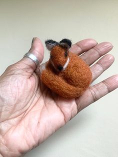 a hand holding a tiny stuffed animal in it's palm