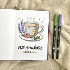 an open notebook with a cup of coffee and two markers