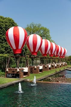 several red and white hot air balloons floating over water