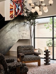 a living room filled with lots of furniture and a painting hanging on the wall next to a stair case