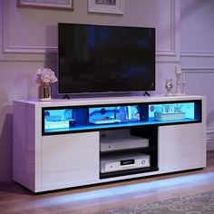 an entertainment center with a flat screen tv mounted on it's side and illuminated shelves