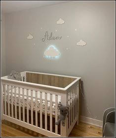 a baby's room with a white crib and clouds on the wall