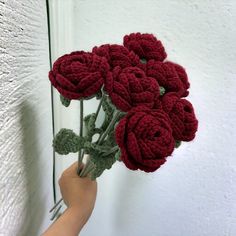 a hand holding a bunch of red crocheted roses