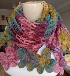 a woman wearing a multicolored scarf with crocheted flowers on the bottom