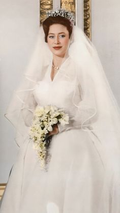 an old photo of a woman in a wedding dress and tiara holding a bouquet