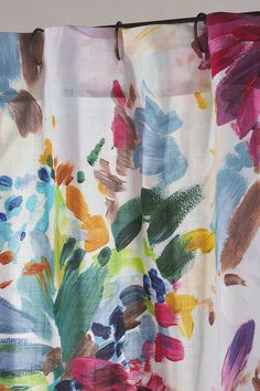 the curtain is open and there are colorful flowers on it in front of a white wall