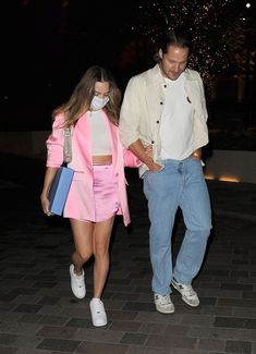 a man and woman walking down a sidewalk at night