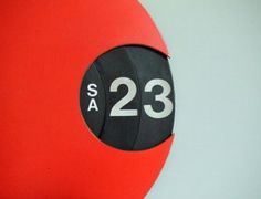 a red and black clock with the number 23 on it's face is shown