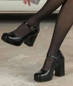 a woman's legs wearing black high heeled shoes with buckles on them