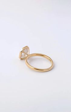 a yellow gold ring with a triangle shaped diamond in the middle, on a white background