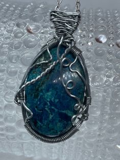 This beautifully wire wrapped Shattuckite necklace with Swarovski Crystal Accent is absolutely gorgeous! We handmade this Shattuckite Cabrochon, and wire wrapped it with stainless steel wire, then hung it on a handmade 18 inches Stainless Steel Chain with a sparkling Swarovski Crystal on the end for an added accent. This Shattuckite is gorgeous with it's variations of bright blues and greens! It will make a lovely piece for any occasion!  Shattuckite is oxidized copper deposits as a secondary, which you can find along with other copper mineral deposits like Chrysocolla and Malachite. Shattuckite is found in many locations around the world, but it's name originated from the Bisbee, Arizona Shattuckite mine where it was discovered by a Pennsylvania man named Lemuel Shattuck in 1888. Lemuel S Artisan Wire Wrapped Chrysocolla Jewelry, Handmade Apatite Pendant Necklace, Wire Wrapped Silver Plated Pendant Necklace, Turquoise Apatite Wire Wrapped Jewelry, Silver Plated Wire Wrapped Pendant Necklace, Unique Hand Wrapped Silver Plated Wire Necklace, Artisan Wire Wrapped Silver Plated Jewelry, Artisan Wire Wrapped Jewelry In Silver Plated Wire, Bisbee Arizona