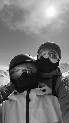 two people wearing helmets and goggles standing in the snow