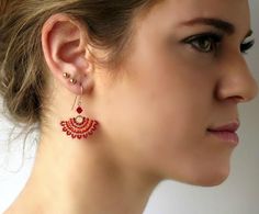 a close up of a person wearing some kind of earring with red beads on it