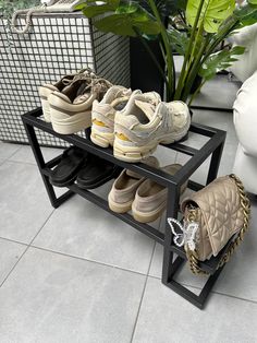 three pairs of shoes are sitting on a black rack with two purses and one shoe