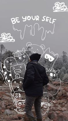 a man standing on top of a rocky hillside next to trees and writing be your self