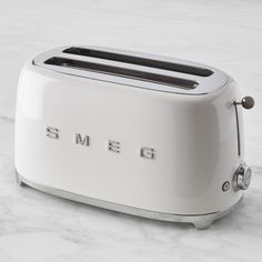 a white toaster with the word smeg on it sitting on a marble surface