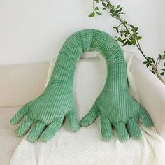 two green gloves sitting on top of a white couch next to a potted plant