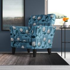 a blue chair sitting on top of a wooden floor next to a vase filled with flowers