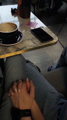 a person sitting at a table with their hands on the edge of a coffee cup