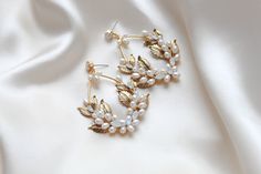 Expertly handcrafted with freshwater pearls and Austrian white opal crystals, our MARGOT Pearl Statement Hoop Earrings are the perfect addition to any bridal look. The antique gold finish adds a touch of opulence, making these large hoop earrings a stunning statement piece for any occasion. Custom-made just for you. - Handcrafted in my PA studio- Genuine Austrian white opal crystal- Freshwater pearls- Antique gold leaves- Available in rose gold, yellow gold or rhodium (silver)- Earrings measure 2-5/8 inches x 2 inches- Handcrafted in the US.- Nickel free and hypoallergenic- PLEASE ALLOW APPROX 10 BUSINESS DAYS FOR COMPLETION BEFORE SHIPPING.This is an original design by © Treasures by Agnes Statement Wedding Earrings, Gold Bridal Hair Comb, Antique Gold Earrings, Statement Earrings Wedding, Bridal Statement Earrings, White Opal Earrings, Statement Hoop Earrings, Rose Gold Bridal, Gold Leaves