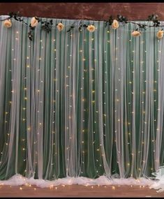 wedding backdrop with flowers and lights on the wall in front of a large curtained window