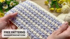 two hands holding up a crocheted dishcloth on a table with flowers in the background