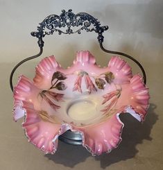 a pink flower shaped bowl sitting on top of a metal stand next to a wall