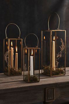 two gold lanterns with candles in them are sitting on a wooden table next to each other