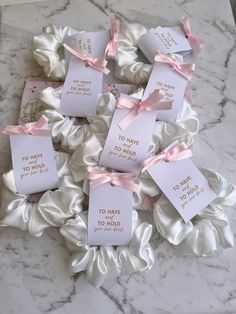 pink and white tags with bows on them sitting on a marble counter top next to flowers