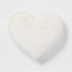 a white heart shaped pillow sitting on top of a table