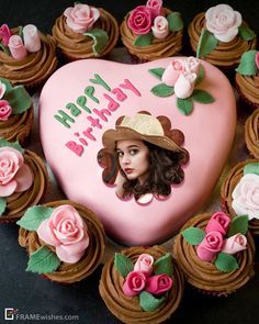 a heart shaped cake decorated with cupcakes and pink frosting, featuring a woman's face