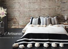 a black and white bed with pom - poms on the bottom, next to a brick wall