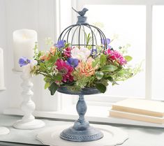 a birdcage filled with flowers sitting on top of a table