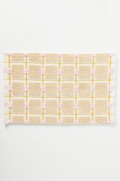 a piece of cloth with yellow and pink squares on it's edge, against a white background