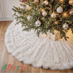 a christmas tree with presents under it on a white rug in front of a fireplace