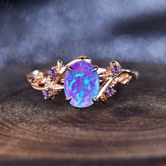 an opal and pink sapphire ring on top of a piece of wood