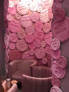 a pink room with lots of hearts on the wall and two chairs in front of it