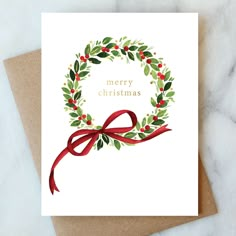 a christmas card with a red ribbon and holly wreath