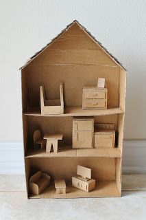 a doll house made out of cardboard sitting on top of a white floor next to a wall