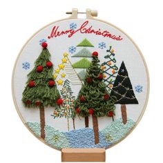 an embroidered christmas scene with trees and snowflakes is shown on a white background