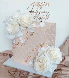 there is a pink cake with white flowers on the top and gold lettering that says, nikkah du almez media