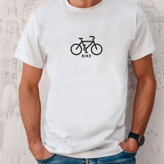 a man standing with his hands in his pockets wearing a white t - shirt that says bike