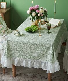 a dining room table with flowers and candles on it, next to an open book